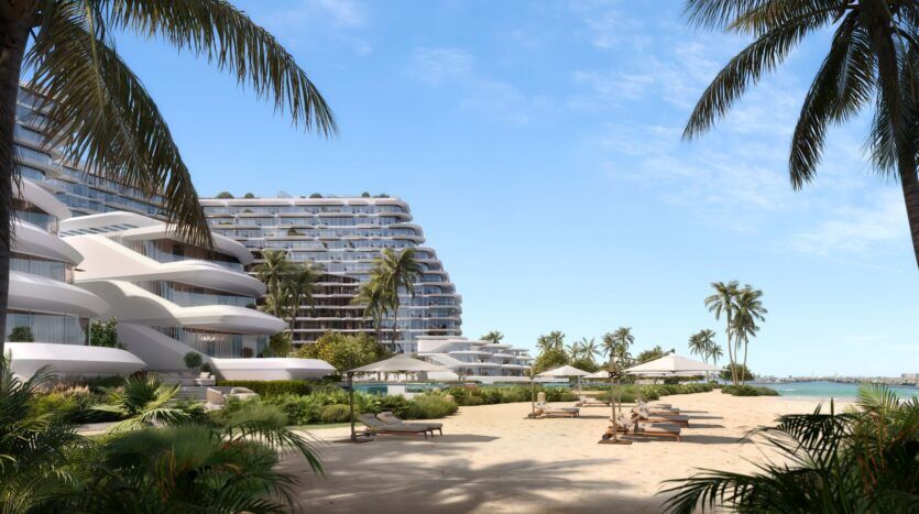 Bella by Passo est un complexe moderne en bord de mer avec des bâtiments blancs incurvés, des palmiers, des chaises longues et des parasols sur une plage de sable donnant sur des eaux bleues calmes sous un ciel clair.