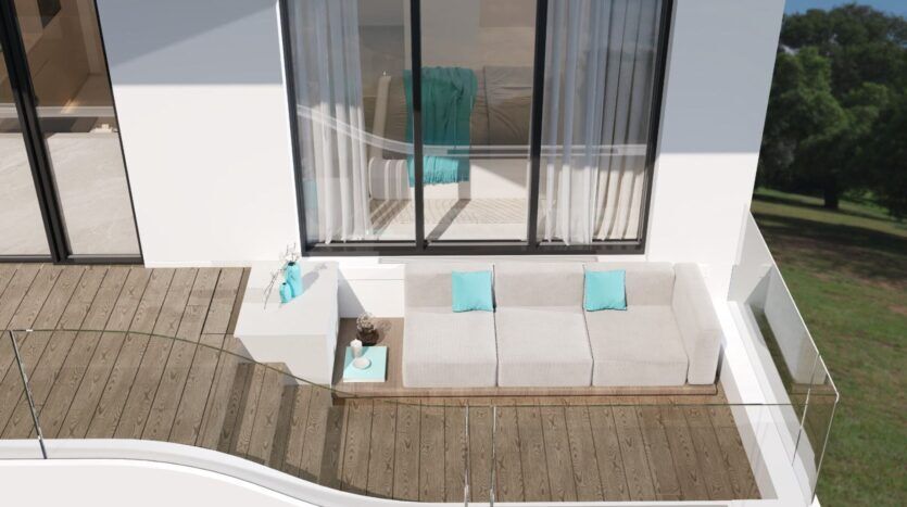Un balcon moderne avec une balustrade en verre et un design inspiré du Reef 996, comprenant un canapé blanc en forme de L avec des coussins turquoise, une petite table d'appoint et un sol en bois, adjacent à une grande fenêtre donnant sur une zone herbeuse.
