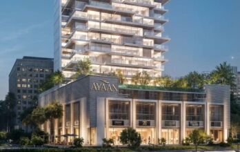 Ayaan Heights 1 by IGO est un immeuble moderne de plusieurs étages baptisé "Ayaan", qui propose des magasins aux étages inférieurs et une tour au-dessus avec des balcons et de la verdure, magnifiquement illuminée le soir.