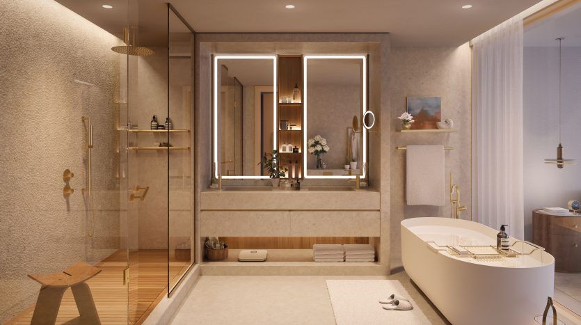 Une luxueuse salle de bains moderne dans une villa de Dubaï avec une grande baignoire, une cabine de douche en verre et deux vasques éclairées par un éclairage ambiant. Des couleurs neutres et chaudes et des plantes décoratives rehaussent l’atmosphère sereine.