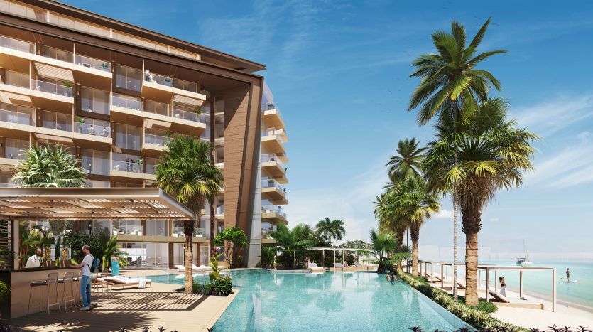 Luxueuse villa en bord de mer à Dubaï avec une piscine à débordement entourée de palmiers. Le bâtiment dispose de plusieurs balcons donnant sur l'océan, où les gens se détendent et d'un espace bar.