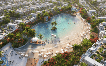 Vue aérienne d'un complexe luxueux doté d'une grande piscine de style lagon entourée d'une végétation tropicale luxuriante et de nombreuses villas blanches sous un ciel ensoleillé dans le sud de Dubaï.