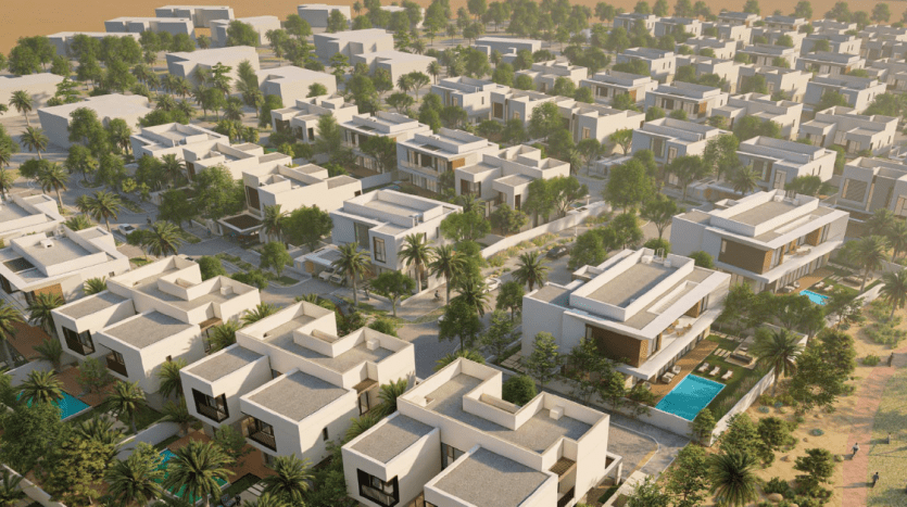 Vue aérienne d'un quartier résidentiel moderne de Dubaï avec des maisons blanches cubiques entourées de palmiers et quelques maisons dotées de piscines privées, dans un cadre désertique au coucher du soleil.