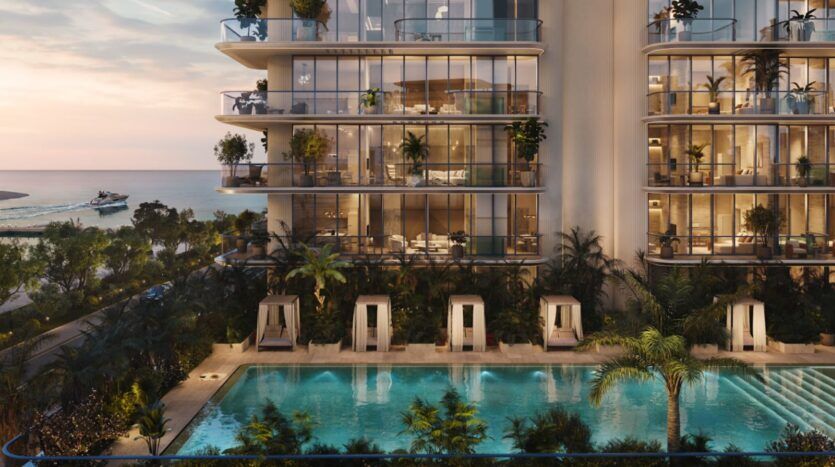 Immeuble d'appartements de luxe en bord de mer, « Le Château Piétrus », avec ses balcons vitrés, sa végétation luxuriante et ses cabines privées au bord d'une grande piscine au coucher du soleil. L'océan et un bateau sont visibles à l'arrière-plan.