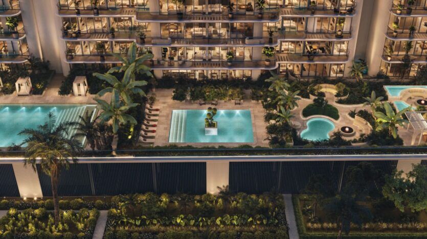 Vue aérienne, de nuit, du luxueux complexe résidentiel « Le Château Piétrus », avec ses balcons illuminés, ses piscines, ses chaises longues, ses palmiers et ses jardins paysagers.