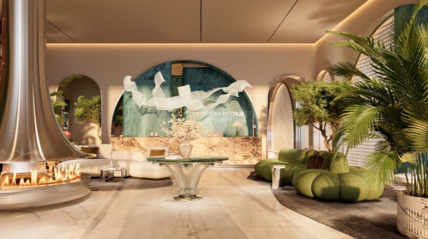 Hall d'entrée luxueux d'un hôtel, avec un sol en marbre, des sièges en velours vert, des fenêtres cintrées, des plantes luxuriantes, une table ronde en verre ornée de fleurs et une cheminée moderne. Le mur du fond présente une décoration élégante et porte l'inscription « Le Château Piétrus ».
