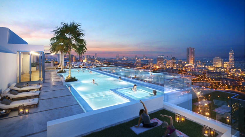 Un luxueux toit-terrasse au crépuscule doté d'une piscine à débordement, de palmiers et d'espaces de détente offrant une vue panoramique sur le paysage urbain bien éclairé de Dubaï.